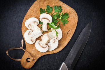 champignon mushroom with parsley and knife  over wooden cutting