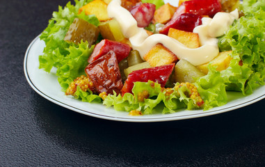 Salad.Chorizo sausage, lettuce, pickled cucumber fried potato with mayonnaise.Dark background