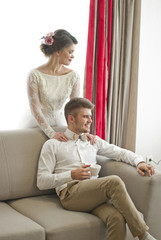 Wedding couple in love. Beautiful bride in white dress with handsome groom. Bright interior with big window. 