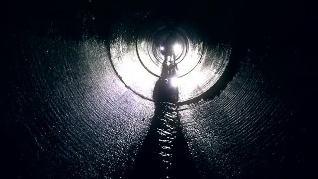 Pair of man looking for orienteering competition check point in dark tunnel.
