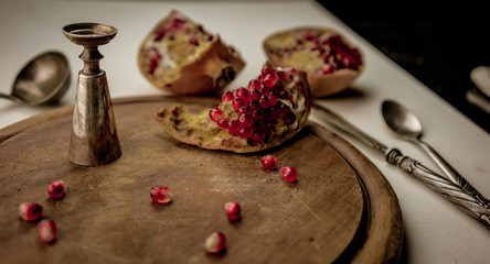 still life. silverware, sliced pomegranate and  grains on a wooden board. close-up.