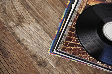 Stack of records on wood, with a vinyl record on top.