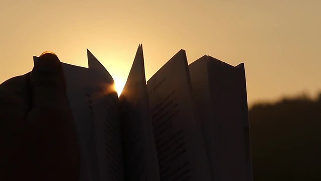 Silhouette of Book at Sunset. Turning Pages in Slow Motion in Sun Lights.