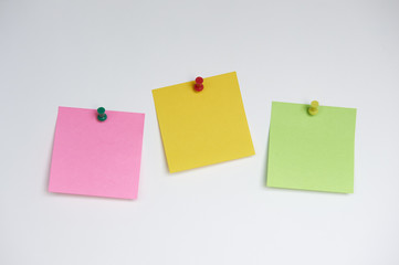 Three sticky notes with push pins on white background