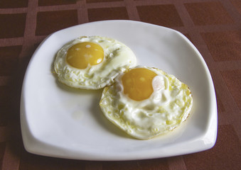 Fried eggs  on a table with a red burgundy cloth in a cage
