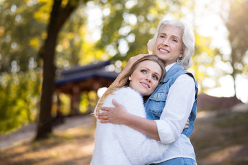 Fototapeta premium Two friendly beautiful women hugging each other in the park.