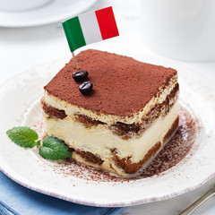 Tiramisu, traditional Italian dessert on a white plate with Italian flag