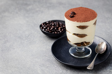 Tiramisu, traditional Italian dessert in glass on a grey stone background Copy space
