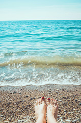 Sea foam, waves and naked woman feet on a sand beach. Girl legs relaxing. Vacation holidays, relax, summer background.  enjoying sun  sunny  day.