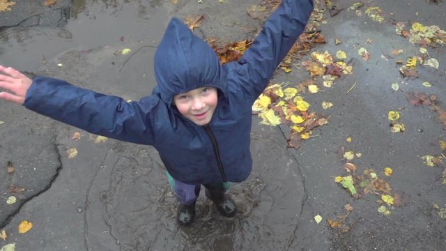 Little boy jumping in muddy puddle, slow motion 250 fps