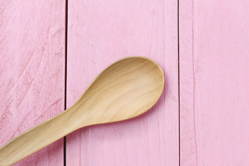 Wooden spoon on pink wood floors.