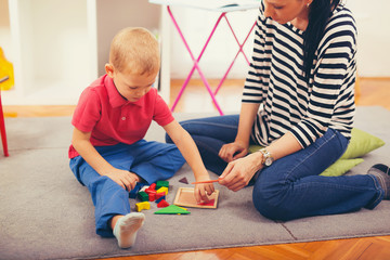 Child boy and mother playing with educational toy