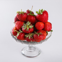 Fresh strawberries in a glass vase on a white background. Vegetarian and healthily cooking concept.selective focus.