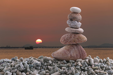 Balance stone on pile rock of sunset background in the evening.