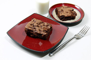 Chocolate chip brownie in a plate with milk and chocolate chips