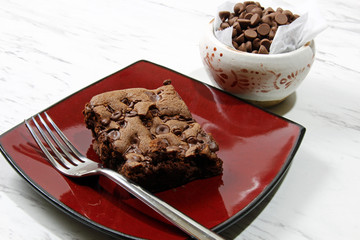 Chocolate chip brownie in a plate with milk and chocolate chips