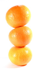 Vertically piled up three ripe oranges isolated on white background, close-up