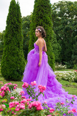 Obraz na płótnie Canvas Beautiful girl in violet dress among in the garden