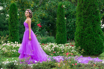 Obraz na płótnie Canvas Beautiful girl in violet dress among in the garden