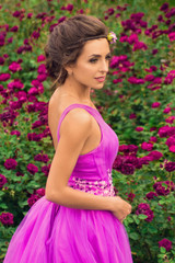 Beautiful girl in violet dress among in the garden