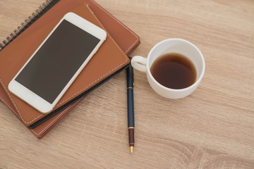 notebook,phone,pen and cup of coffee on work desk