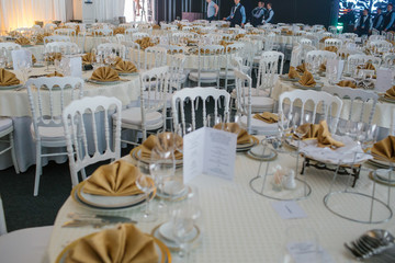 White tables served in rich style stand in big restaurant hall