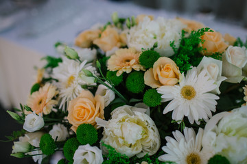 Beige roses and white flowers make a beautiful bouquet