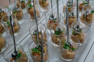 Steel spoons stand straight in glasses with salted fish