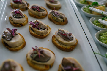 Slices of mushrooms decorate little snacks made of bread and fis