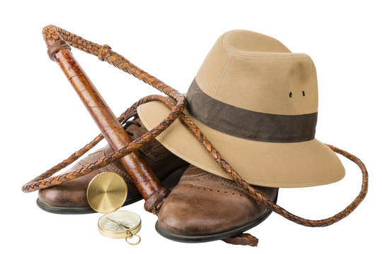 Travel and adventure concept. Vintage brown shoes with fedora hat, bullwhip and compass isolated