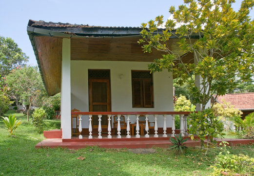 Typical colonial style bungalow with veranda and wide roof in green garden surroundings in December in Sri Lanka, Asia.