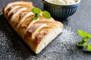 Braided strudel stuffed with curd and raisins, sprinkled with icing sugar