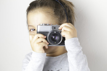 Naklejka premium Little girl takes picture with vintage camera