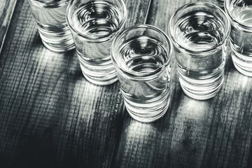 Crédence de cuisine en verre imprimé Bar Vodka shots in a row filled with alcohol on wooden black bar.