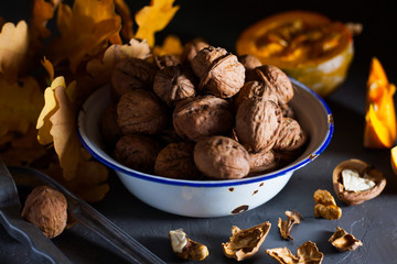 Walnuts in a bowl on a gray background and sliced pumpkin on the table