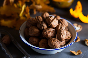 Walnuts in a bowl on a gray background and sliced pumpkin on the table