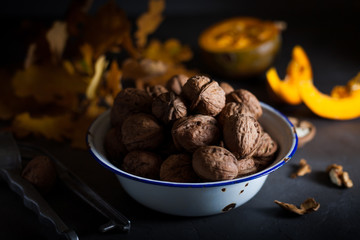 Walnuts in a bowl on a gray background and sliced pumpkin on the table