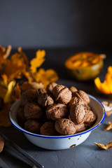 Walnuts in a bowl on a gray background and sliced pumpkin on the table