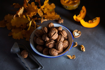 Walnuts in a bowl on a gray background and sliced pumpkin on the table