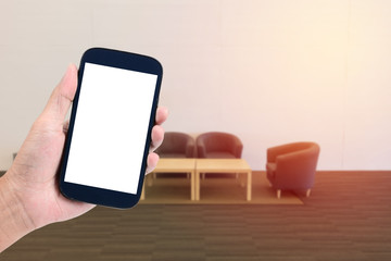 man hand holding the phone tablet with blurred empty sofa set ba
