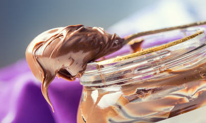 Chocolate spread in spoon. A jar of hazelnut chocolate spread. - obrazy, fototapety, plakaty