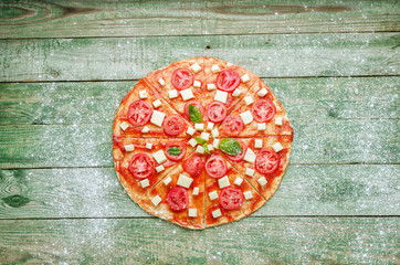 Fototapeta na wymiar Raw pizza with flour on green wood table. Top view