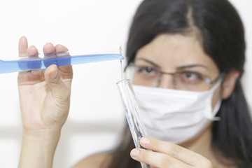Naklejka premium Young chemical female researcher holding two glass tubes with fluid in laboratory