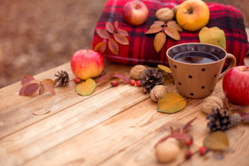 Autumn composition on a wooden background. Still life, food and drink, apples, pumpkin, nuts, cone, tea.