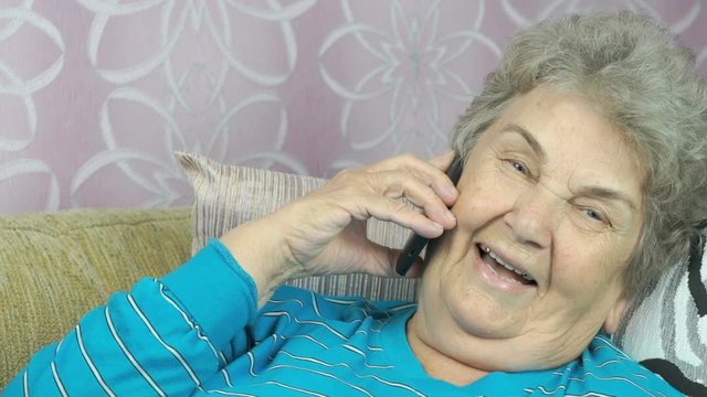 Senior woman with smartphone calling at room