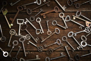 Fototapeta premium many different keys on brown wooden background. 