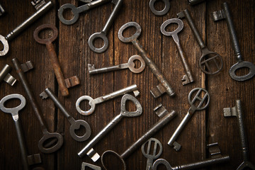 Fototapeta premium many different keys on brown wooden background. 