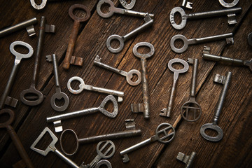 many different keys on brown wooden background.
