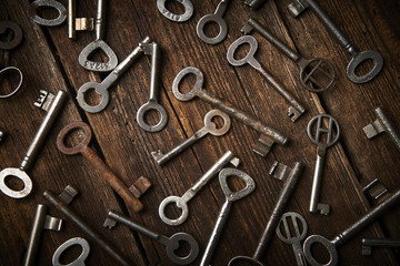 many different keys on brown wooden background.
