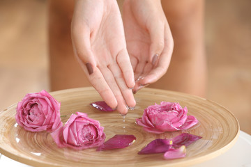 Obraz na płótnie Canvas Female hands in spa wooden bowl with flowers, closeup